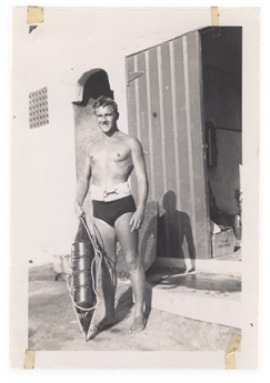 Black and white photo of young man about to go swimming.